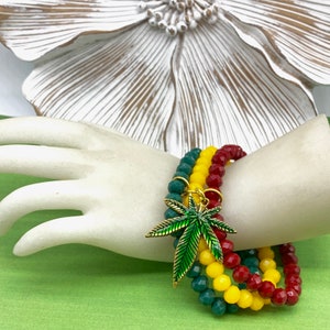 May include: Three layered beaded bracelets in red, yellow, and green with a green and gold marijuana leaf charm.