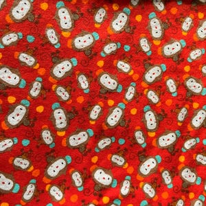 May include: Red fabric with a repeating pattern of cartoon monkeys. The monkeys have white faces, brown bodies, and blue hats. Orange and yellow polka dots are scattered throughout the design.