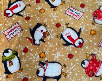 Tela de franela de algodón con pingüinos invernales: negro, blanco, rojo y dorado sobre fondo tostado; 109,5 cm x 1,9 m; tela navideña