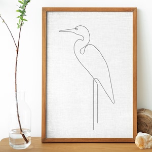 May include: A black and white line drawing of a heron standing on one leg, framed in a natural wood frame.
