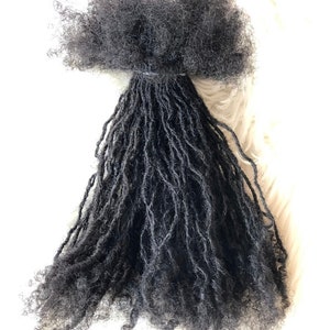 Op de afbeelding: Een bundel zwarte dreadlocks van mensenhaar, klaar om aan een kapsel te worden toegevoegd.