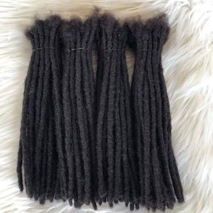 Könnte beinhalten: Ein Set mit vier schwarzen Dreadlock-Haarverlängerungen. Die Dreadlocks sind gebündelt und haben ein natürliches, strukturiertes Aussehen.