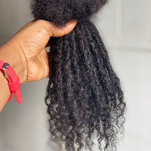 May include: A bundle of black human hair extensions in dreadlocks style.