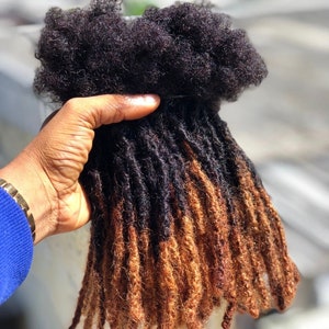 Op de afbeelding: Een set bruine en zwarte dreadlock haarverlengingen. De dreadlocks zijn lang en dik, met een natuurlijke textuur.