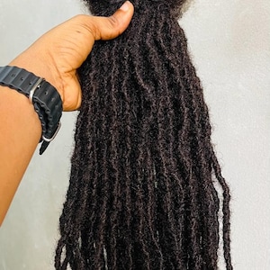 Op de afbeelding: Een bundel lange, zwarte dreadlocks met een elastiekje aan de bovenkant.