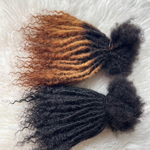 Puede incluir: Dos paquetes de extensiones de cabello rizado. Uno es un degradado de marr&oacute;n a marr&oacute;n claro, el otro es negro. El cabello est&aacute; peinado en rastas con una textura rizada. El fondo es una superficie blanca y esponjosa.