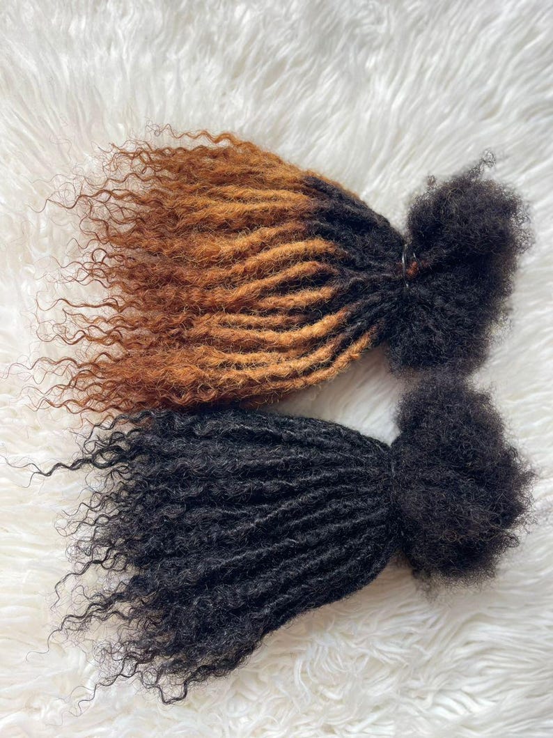 Puede incluir: Dos paquetes de extensiones de cabello rizado. Uno es un degradado de marr&oacute;n a marr&oacute;n claro, el otro es negro. El cabello est&aacute; peinado en rastas con una textura rizada. El fondo es una superficie blanca y esponjosa.