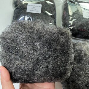May include: A close-up of a bundle of Afro kinky human hair in salt and pepper color. The hair is 10 inches long and is packaged in a clear plastic bag.