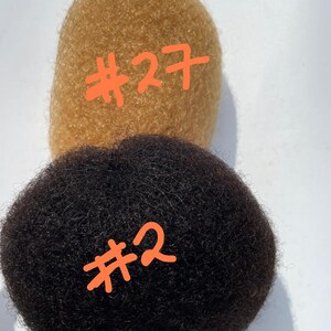 May include: Two afro hair bundles, one is a light brown color labeled #27 and the other is black labeled #2.
