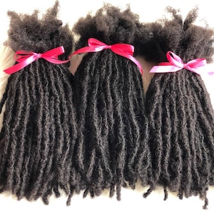 May include: Three bundles of black human hair dreadlocks tied with pink ribbons.