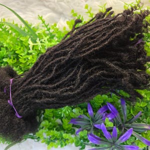 May include: A bundle of dark brown human hair dreadlocks. The dreadlocks are long and thick, and they are arranged in a loose, flowing style.