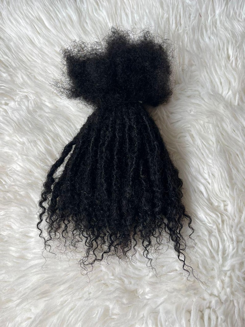 Puede incluir: Un paquete de extensiones de cabello negro, rizado y apretado. El cabello est&aacute; peinado con un patr&oacute;n natural de tipo afro con mechones individuales muy enrollados. El cabello est&aacute; dispuesto sobre una superficie blanca y esponjosa.