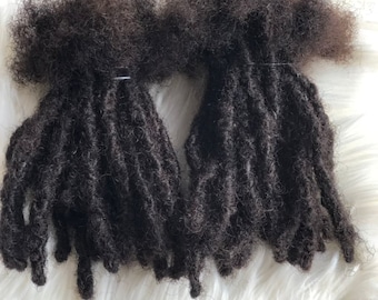 May include: Two bundles of dark brown human hair dreadlocks. The dreadlocks are tied together with a rubber band.