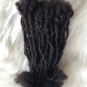 Puede incluir: Un paquete de rastas de color marr&oacute;n oscuro, probablemente extensiones de cabello, sobre un fondo blanco y esponjoso. Las rastas est&aacute;n enrolladas y parecen estar hechas de cabello natural.