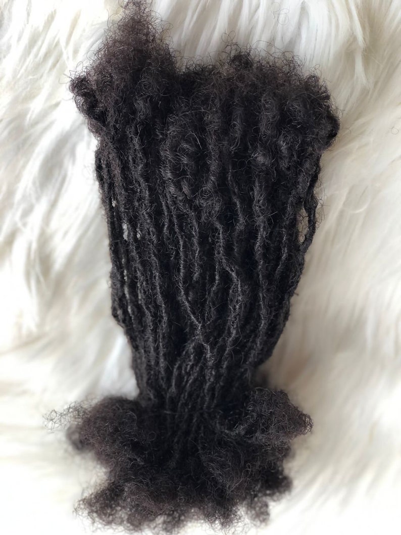 Puede incluir: Un paquete de rastas de color marr&oacute;n oscuro, probablemente extensiones de cabello, sobre un fondo blanco y esponjoso. Las rastas est&aacute;n enrolladas y parecen estar hechas de cabello natural.