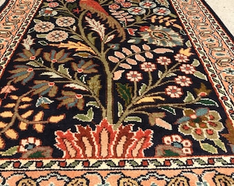 May include: A long, narrow rug with a dark blue background and a floral pattern. The rug features a central tree with birds and flowers in shades of red, green, yellow, and pink. The rug has a border with a paisley design.