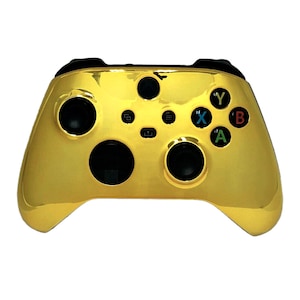 May include: A gold-colored Xbox controller with black buttons and a black faceplate. The buttons are labeled A, B, X, and Y.