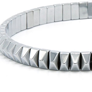 May include: A silver bracelet with a row of pyramid-shaped beads.
