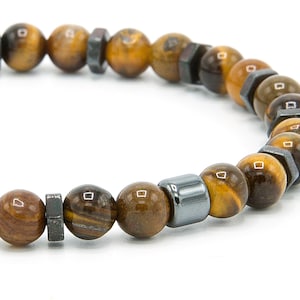 May include: A brown and gold beaded bracelet with silver accents. The bracelet is made of tiger's eye and hematite beads.