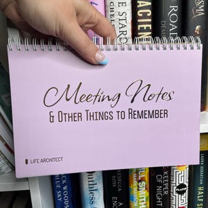 May include: A lavender notebook with a gold spiral binding and the text "Meeting Notes & Other Things to Remember" in gold lettering. The notebook is labeled "Life Architect" in the bottom left corner.