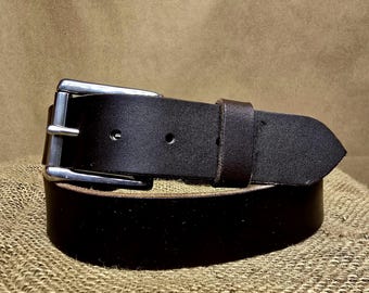 May include: A dark brown leather belt with a silver-colored buckle. The belt is made of thick, sturdy leather and has several holes for adjustment. The buckle is rectangular and has a simple, classic design. The belt is approximately 1.5 inches wide.