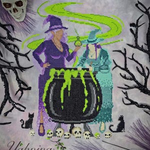 May include: Cross-stitch design titled "Spellbound" featuring two witches, a bubbling cauldron, black cats, and skulls. The witches are dressed in purple and teal, with green smoke rising from the cauldron. The design includes the text "Spellbound" and "Yahnina Designs".