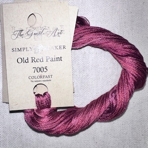 May include: A skein of Old Red Paint 7005 colorfast embroidery floss. The floss is a deep, rich burgundy color, and is twisted into a loop. A cardboard tag with the text "The Gentle Art" and "Simply Shaker" is attached.