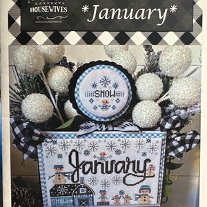 May include: A cross-stitch pattern for January, featuring a winter scene with snowmen, a house, and snowflakes. The pattern is titled "January" and includes the text "Let it snow" three times.