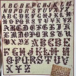 May include: A cross-stitch sampler featuring four red alphabets in various fonts. The text "Four Red Alphabets" is at the top. The sampler includes a smaller version of the alphabets in the bottom right corner. The NeedleWorkPress logo is at the bottom.