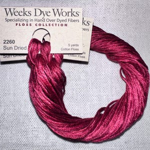May include: A skein of Weeks Dye Works "Sun Dried" cotton floss in a deep red hue. The floss is wrapped around a cardboard label that reads "FLOSS COLLECTION" and "5 yards". The label also includes the number "2260".