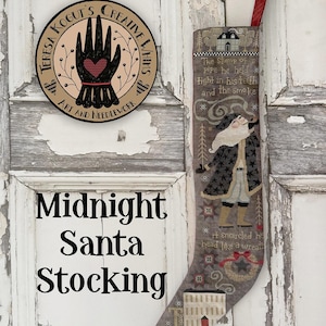 May include: A decorative Christmas stocking with a Santa Claus design, featuring text that reads "Midnight Santa Stocking." The stocking is gray with a red ribbon for hanging. A round sign with a hand graphic is also visible.