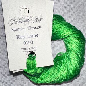 May include: A skein of bright green embroidery floss, labeled "Key Lime 0193" by The Gentle Art Sampler Threads. The floss is a vibrant, spring green color and is labeled as colorfast.