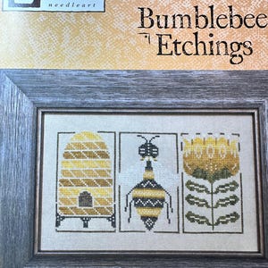May include: A framed cross-stitch design featuring a beehive, a bumblebee, and a yellow flower. The design is titled "Bumblebee Etchings" and is from the Heart in Hand needleart collection.