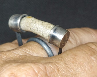 Puede incluir: Un anillo de plata con una piedra blanca engastada en una banda de plata. El anillo se lleva en un dedo.