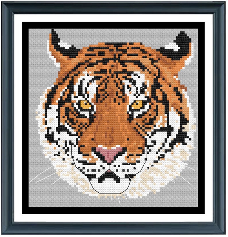 Puede incluir: Primer plano de la cara de un tigre con rayas naranjas y negras. El tigre tiene un hocico blanco y bigotes. El fondo es gris claro.