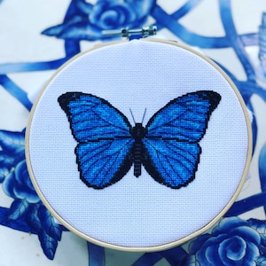 May include: A blue butterfly cross-stitch embroidery in a wooden embroidery hoop.
