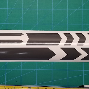 May include: A sheet of gray vinyl bike frame decals with a variety of arrow shapes. The decals are designed to be applied to the frame of a bicycle.