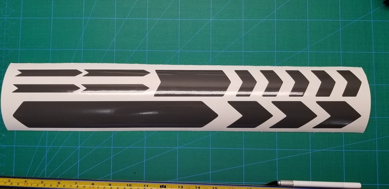 May include: A sheet of gray vinyl bike frame decals with a variety of arrow shapes. The decals are designed to be applied to the frame of a bicycle.