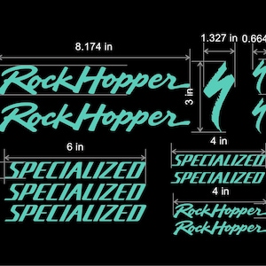 May include: A set of turquoise blue vinyl decals for a bicycle. The decals include the words "Rock Hopper" and "Specialized" in a stylized font. The decals are approximately 8.17 inches wide and 3 inches tall.