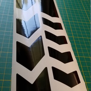 May include: Black and white chevron pattern vinyl sticker with a glossy finish. The sticker is designed to be applied to a vehicle or other surface.