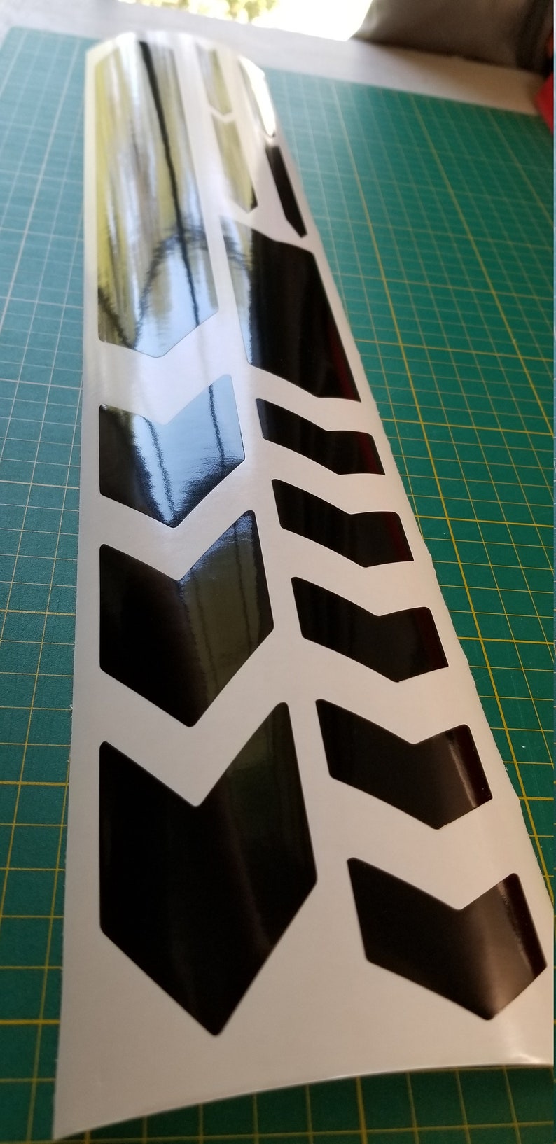 May include: Black and white chevron pattern vinyl sticker with a glossy finish. The sticker is designed to be applied to a vehicle or other surface.
