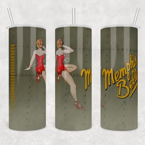 Puede incluir: Tres vasos de acero inoxidable con un patrón de camuflaje verde y marrón. El vaso del centro presenta una ilustración de una chica pin-up. El vaso de la derecha tiene el texto "Memphis Belle" en amarillo.