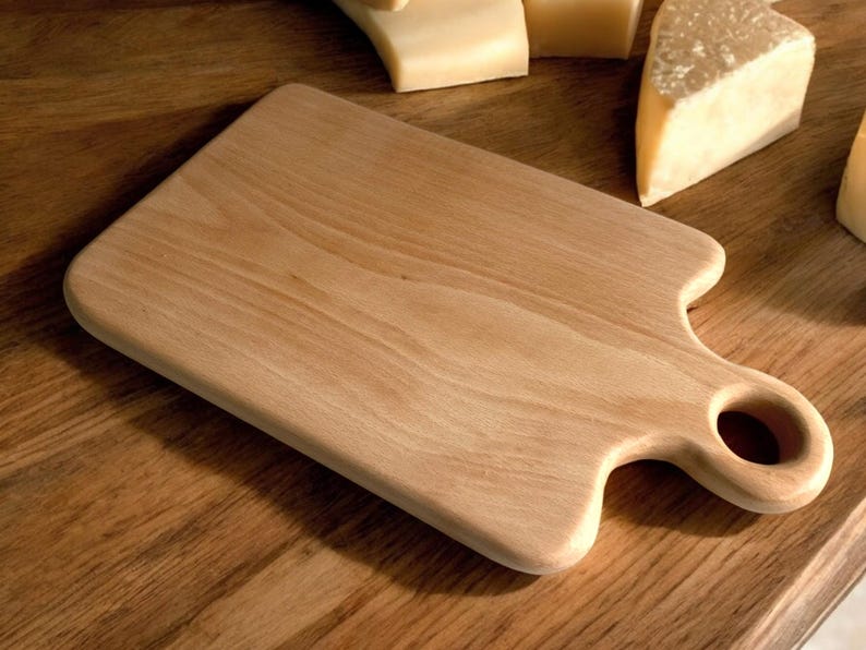 May include: A light brown wooden cutting board with a handle and a hole in the handle. The board is on a wooden surface.