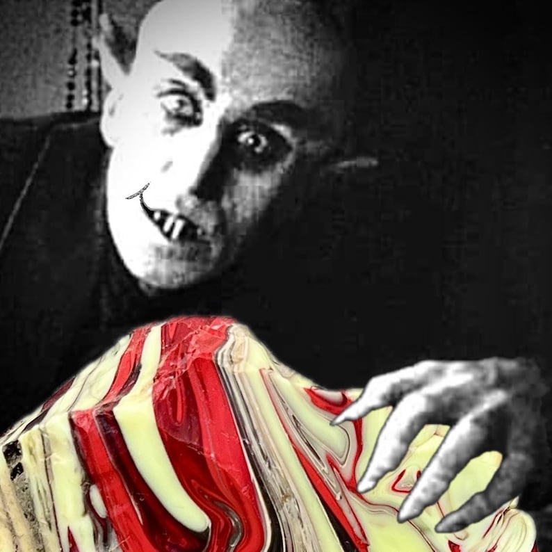 May include: Black and white image of a vampire with a sinister expression, looking down at a colorful, abstract object with red, white, and yellow swirls. The vampire's hand is reaching towards the object.