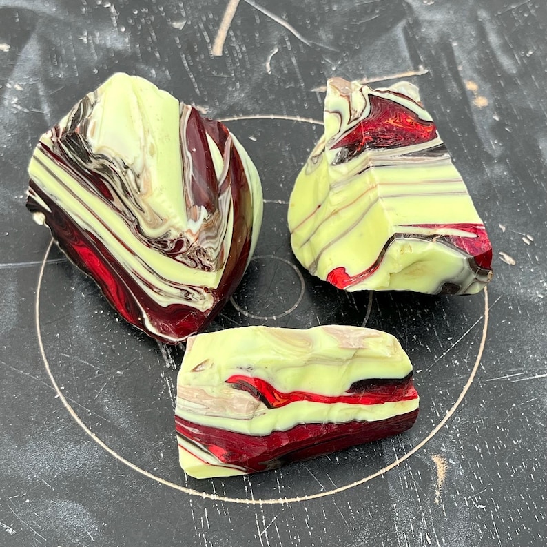 May include: Three pieces of decorative glass with a marbled pattern. The glass features a mix of colors, including yellow, burgundy, red, and brown. The pieces have irregular shapes and appear to be hand-crafted.