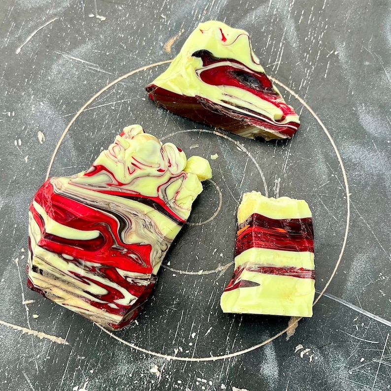May include: Three abstract, colorful, rock-like sculptures. The pieces feature a mix of red, yellow, and brown hues, with a marbled effect. The shapes vary in size and form, creating a unique artistic display.