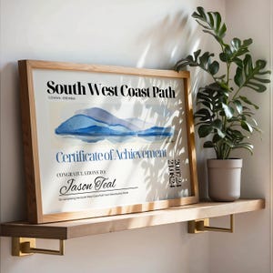 May include: A framed certificate of achievement for completing the South West Coast Path, a 630-mile trail. The certificate features a watercolour illustration of a coastline and the text "Congratulations to: Jason Teal".