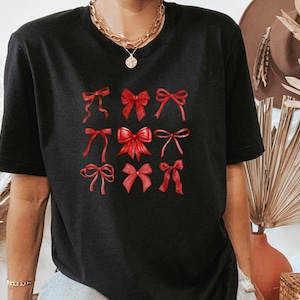 Op de afbeelding: Zwart T-shirt met een afbeelding van negen rode strikken in verschillende stijlen.
