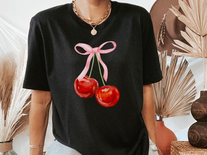 May include: Black t-shirt with a pink ribbon and two red cherries printed on the front.