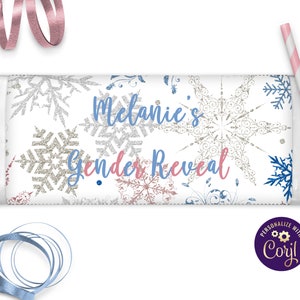 May include: A white chocolate bar wrapper with a snowflake pattern and the text "Melanie's Gender Reveal".